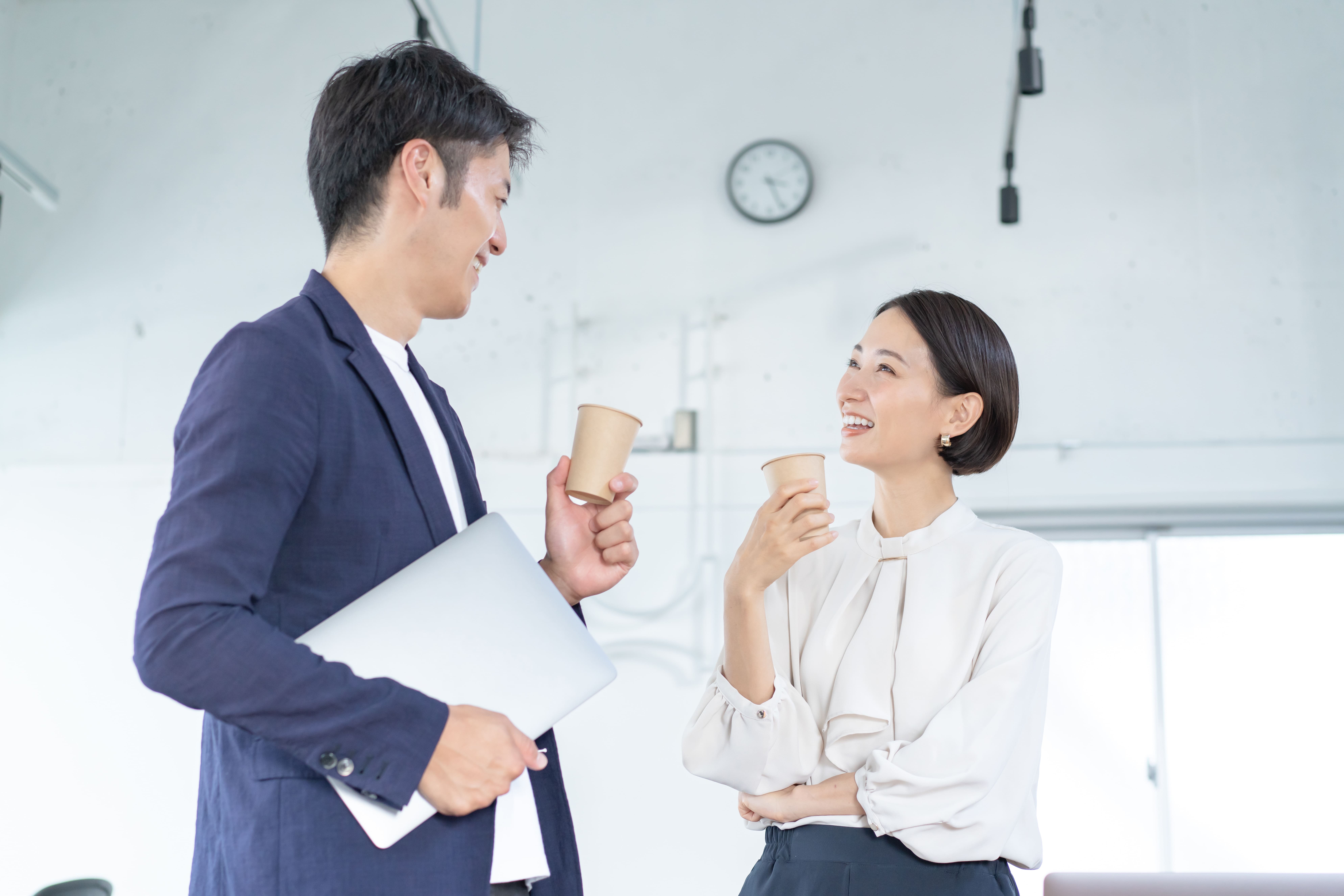 オフィスに設置されたカフェスペースでコーヒーを楽しみながらコミュニケーションを取るビジネスパーソンの様子