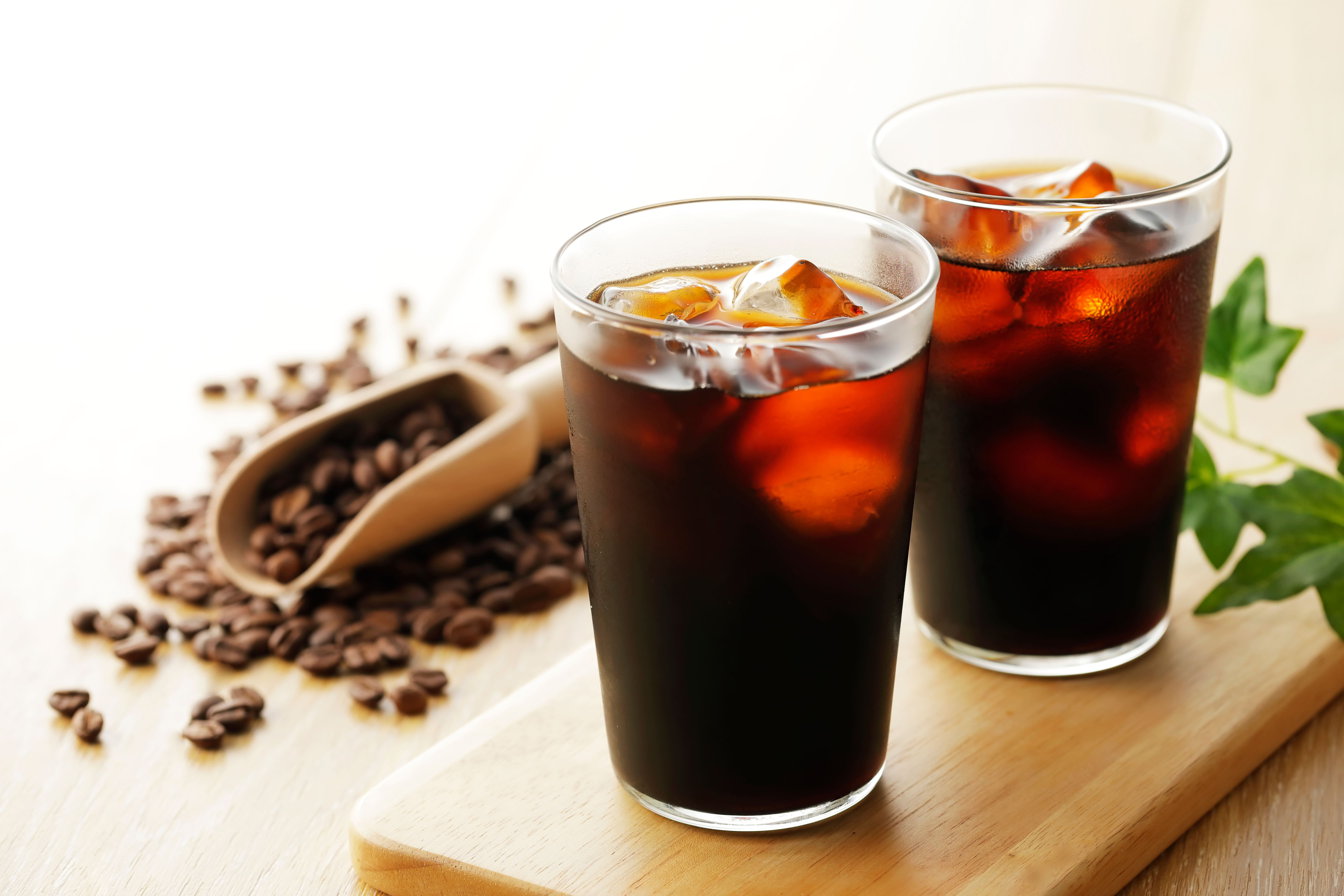 木製トレーに並んだ2杯のアイスコーヒーとコーヒー豆