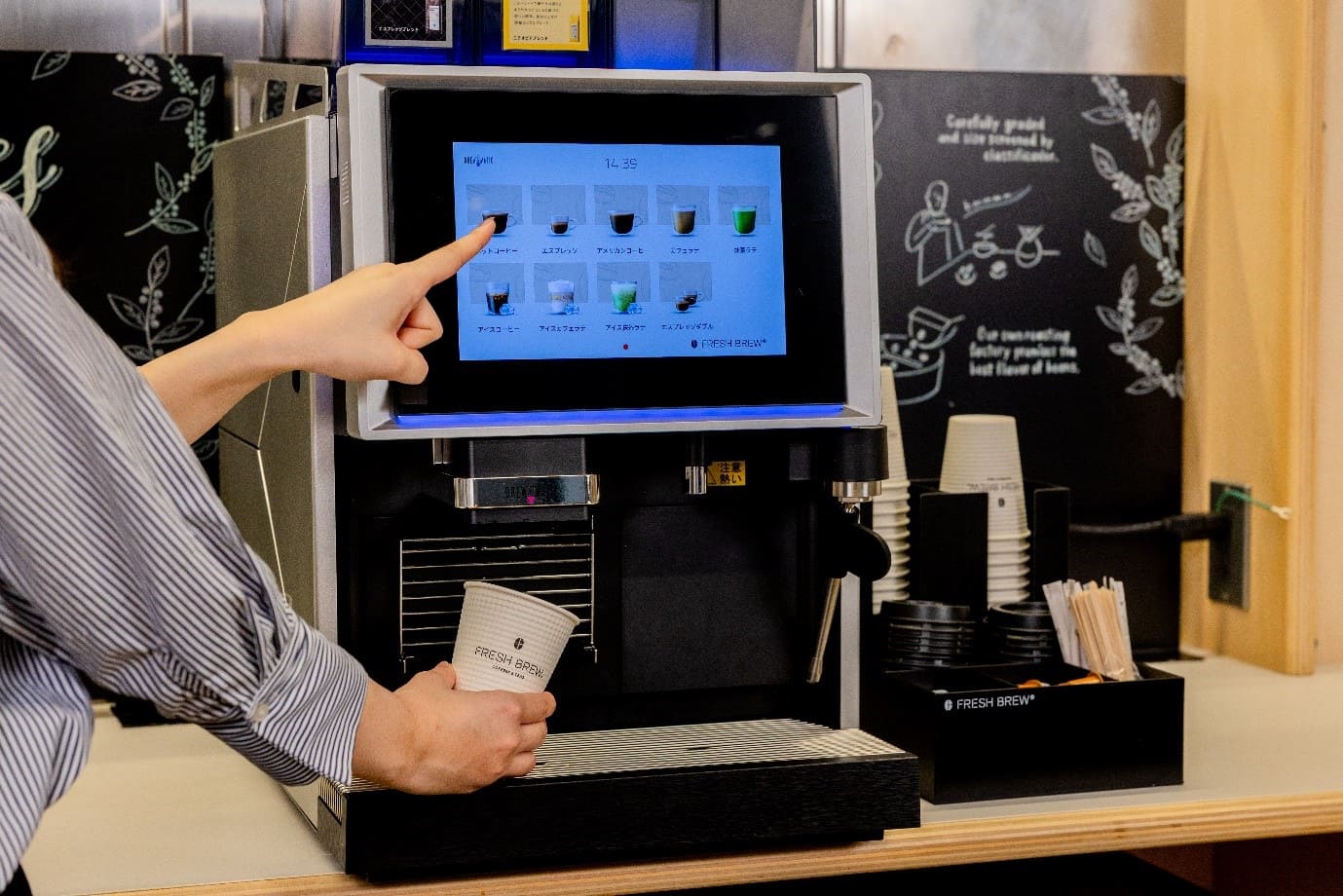 エームサービスのオフィスドリンクサービスでFRESH BREW業務用コーヒーマシンのタッチパネルを操作する様子