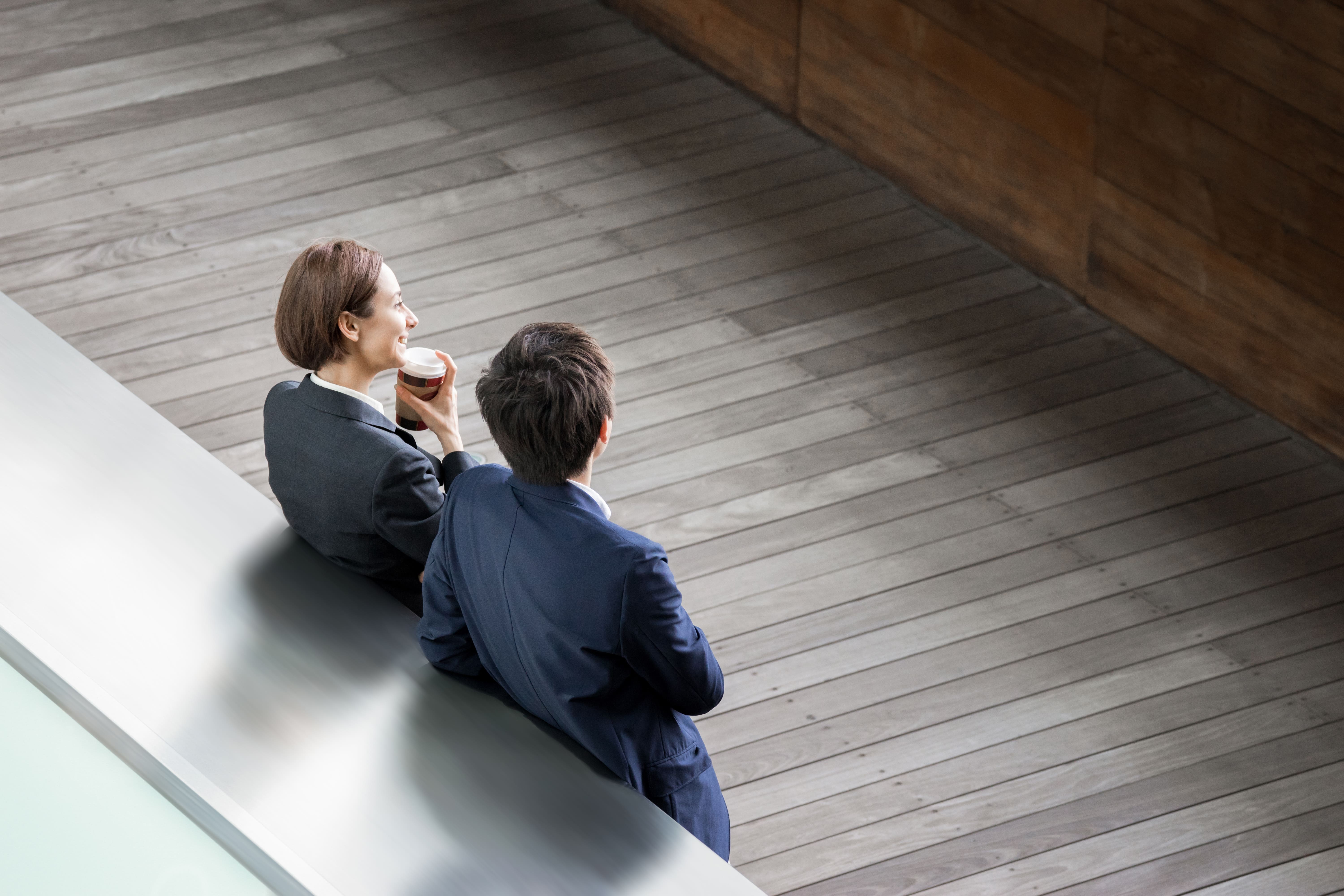 ウッドデッキ風のオフィス空間でコーヒーを片手に過ごすビジネスシーン