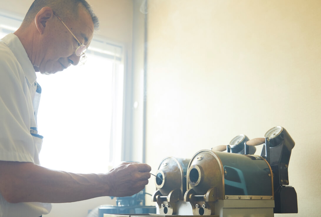 珈琲焙煎士が工場でコーヒー豆の焙煎作業に向き合う様子