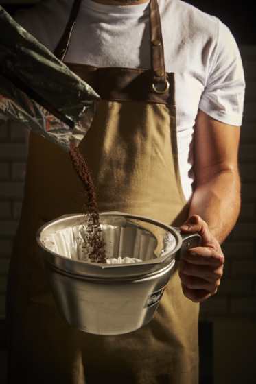 エプロンを着たバリスタがスターバックスのコーヒー体験をお届けするコーヒーをフィルターに入れている様子